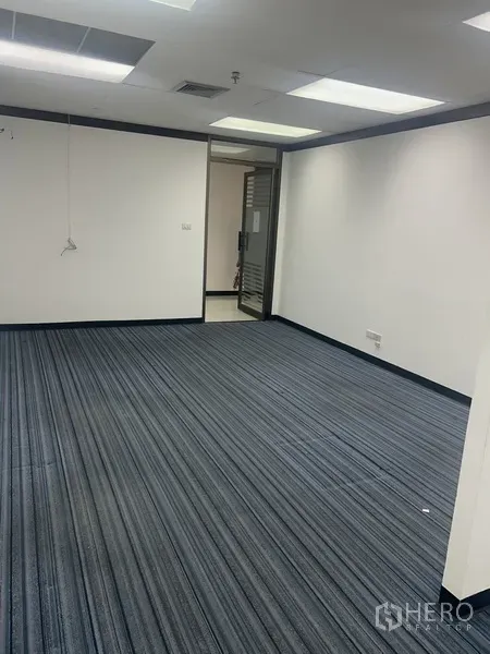 Office Space for rent in Pathum Wan, Bangkok - Bright office area with striped carpet flooring, white walls and a glass entry door.