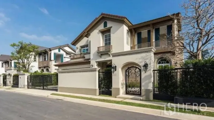 Detached House for rent in Bang Phli, Samut Prakan - Gated luxury detached house with stucco facade, balconies and wrought-iron gate.
