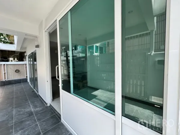 Home Office for rent in Watthana, Bangkok - Ground-floor terrace with sliding glass doors and dark floor tiles.
