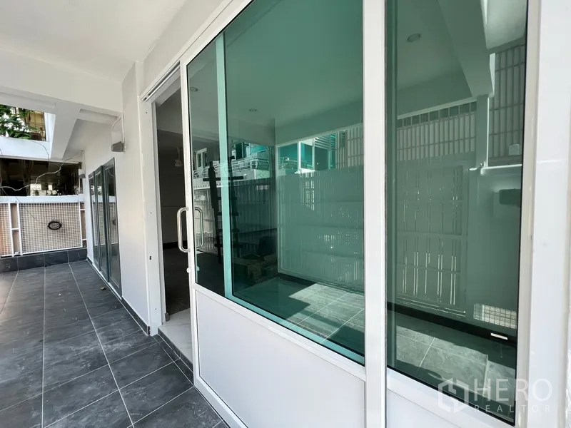 Home Office for rent in Watthana, Bangkok - Ground-floor terrace with sliding glass doors and dark floor tiles.