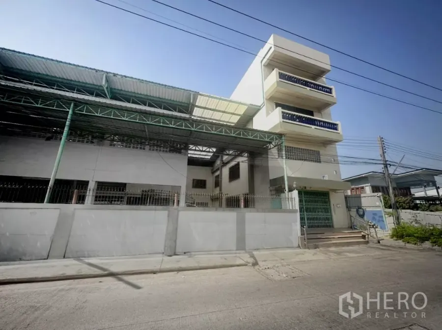 Warehouse for rent or sale in Thanyaburi, Pathum Thani - Street view of gated warehouse with covered loading canopy and attached office block in Thanyaburi.