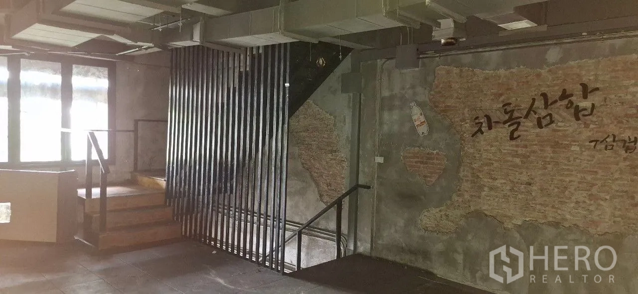 Shophouse for rent or sale in Watthana, Bangkok - Upper floor with staircase, exposed HVAC ducts, and a feature wall with textured brick accents.