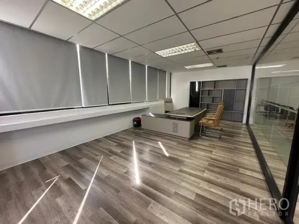Office Space for rent or sale in Din Daeng, Bangkok - Private executive office with large desk, blinds, wood-style flooring and a glass partition.