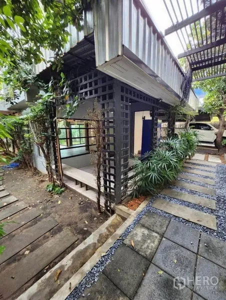 สำนักงานที่บ้าน ให้เช่าในLat Phrao, Bangkok - มุมอาคารสไตล์อินดัสเทรียล มีโครงระแนง ช่องลม และทางเดินหินท่ามกลางสวน