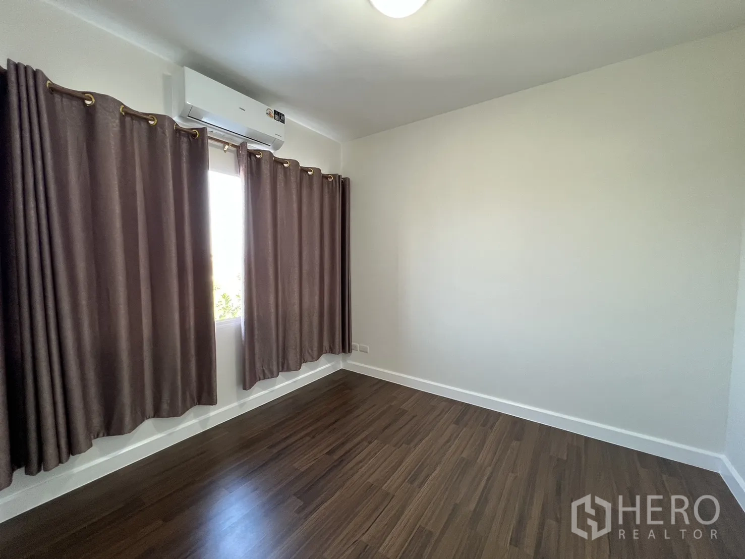 Townhouse for rent in Bang Kapi, Bangkok - Empty third bedroom with wood-tone flooring and curtains.