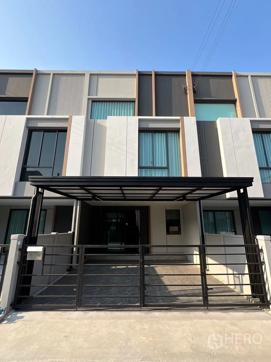 Townhouse for rent in Bang Phli, Samut Prakan - Modern townhouse exterior with a gated covered carport and tall windows.