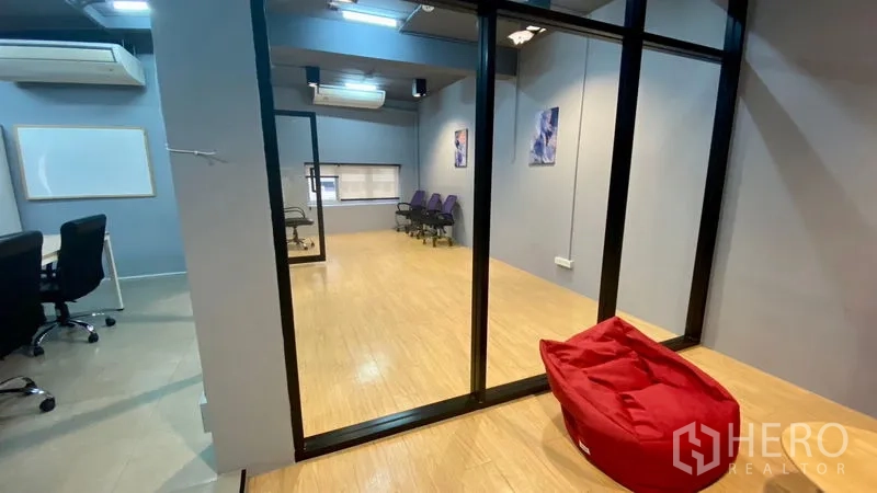 Office Space for rent in Sathon, Bangkok - Glass-walled room opening to a bright multipurpose space with wooden floors and seating.