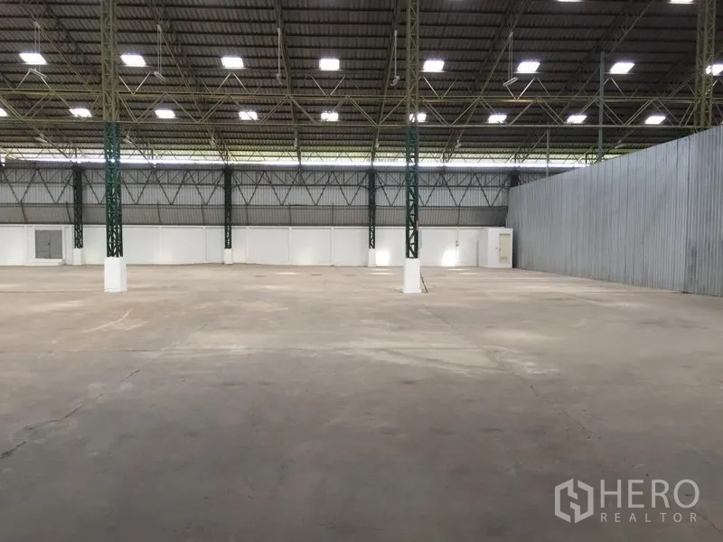 Warehouse for rent in Mueang Pathum Thani, Pathum Thani - Open storage bay with wide column spacing, insulated roof panels and white partition wall.