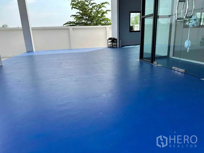 Warehouse for sale in Khlong Luang, Pathum Thani - Blue epoxy floor terrace next to the glass entrance and perimeter wall.