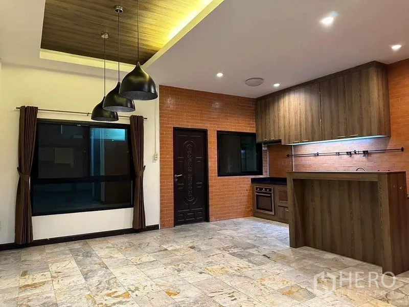 联排别墅 出租在Phaya Thai, Bangkok - 开放式厨房，砖面防溅板、木质橱柜、吧台与黑色吊灯。