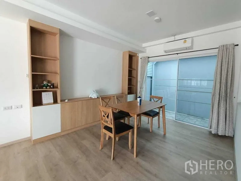Townhouse for rent in Prawet, Bangkok - Dining area with wooden table and chairs, built-in cabinets and sliding door to side terrace.