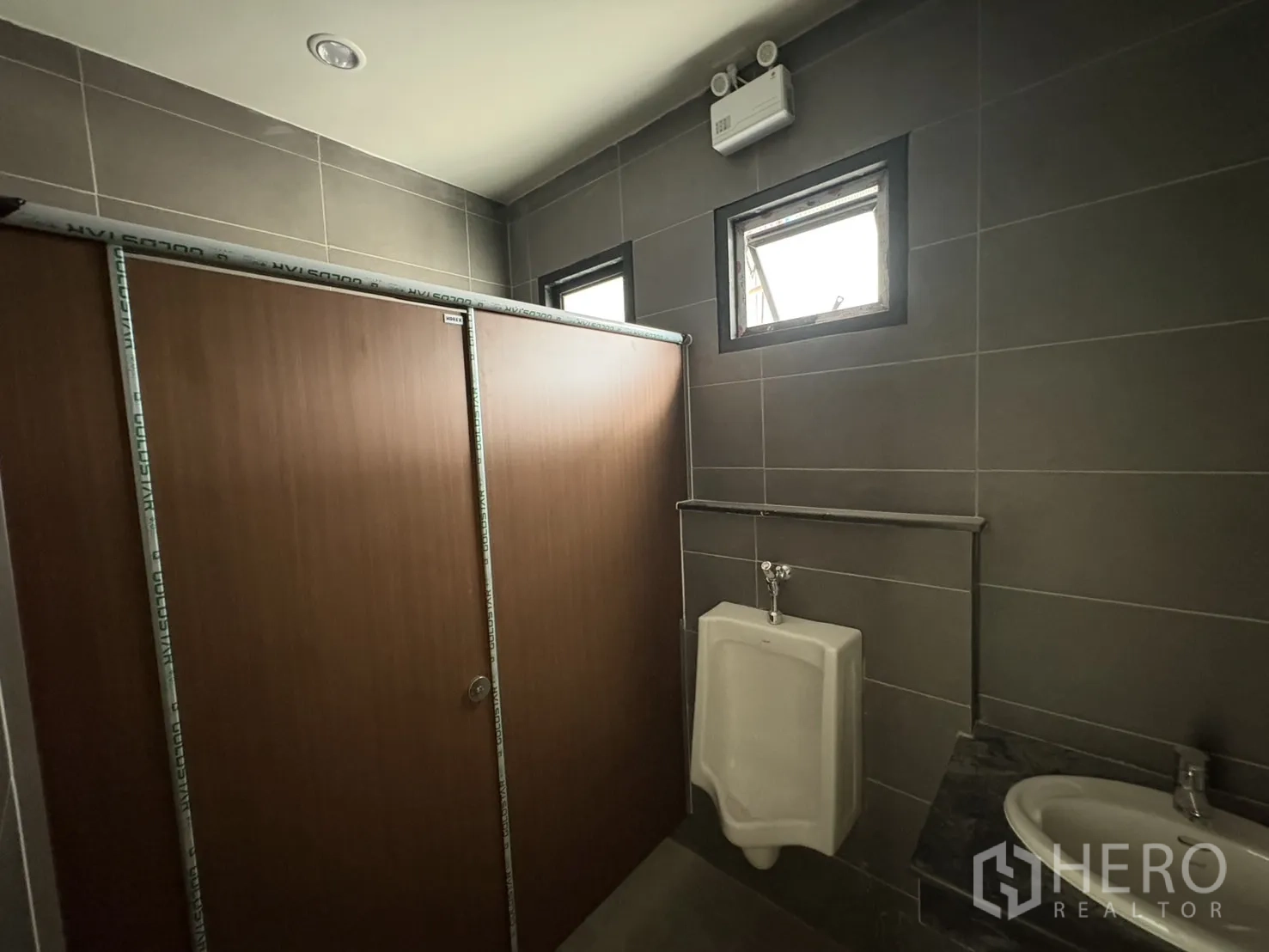 Factory for rent in Bang Pakong, Chachoengsao - Restroom with urinal, partitions, and ventilation windows.