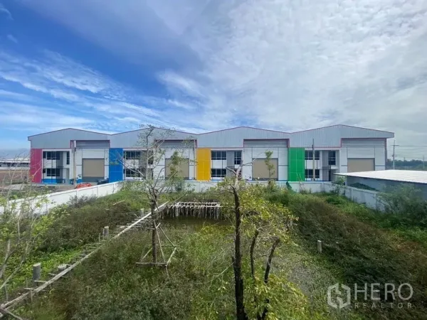 Warehouse for rent in Bang Phli, Samut Prakan - Row of modern warehouses with colorful facades and loading bays in Bang Phli under a blue sky.