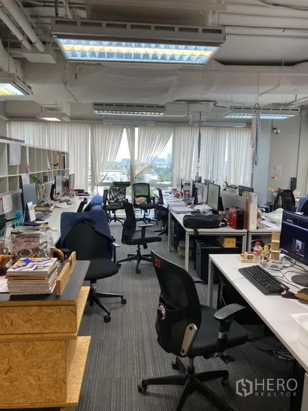 办公空间 出租在Khlong Toei, Bangkok - 明亮工区，多张办公桌与天花灯，窗外为城市景色。