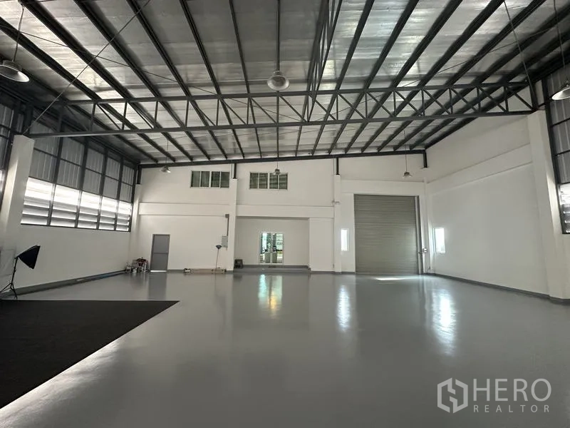 Factory for sale in Lam Luk Ka, Pathum Thani - Warehouse space with wide roller door, ventilation panels and clear span.