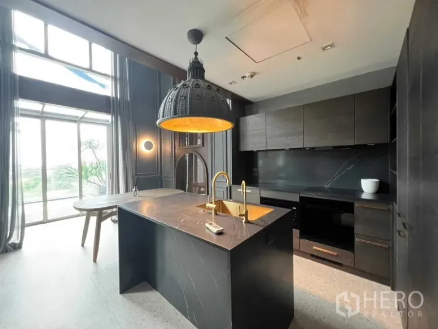 Condominium for sale in Khlong Toei, Bangkok - Gourmet kitchen with marble island, dome pendant light and full-height windows.