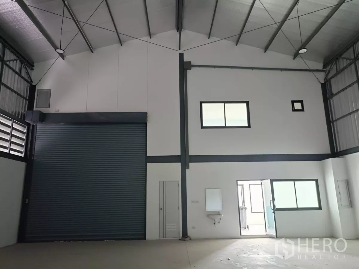 Factory for rent or sale in Bang Yai, Nonthaburi - Loading area inside the warehouse with a large roller shutter and attached office section.