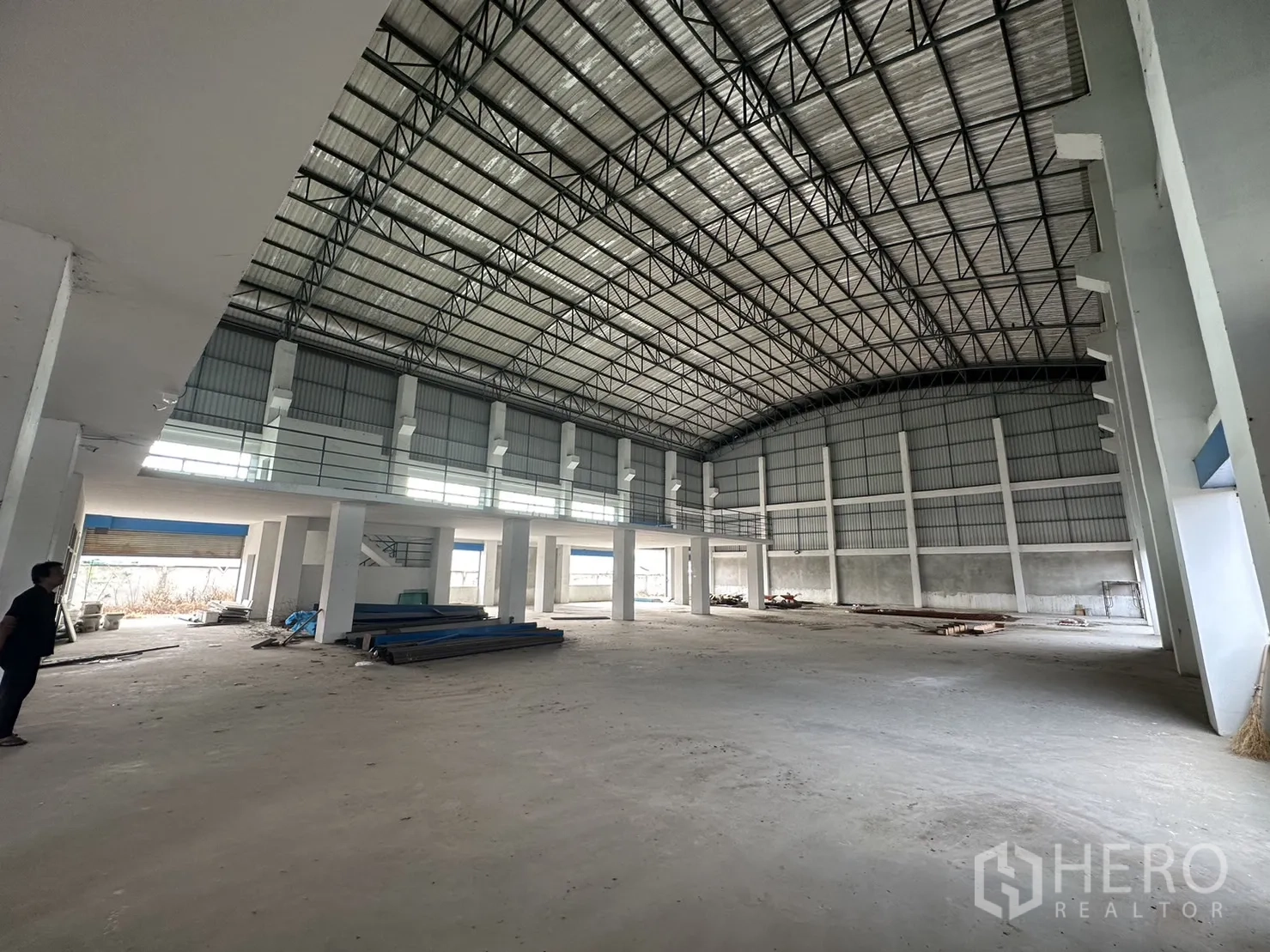 Factory for rent in Pak Kret, Nonthaburi - Open warehouse interior featuring mezzanine, tall columns and natural light from side windows.