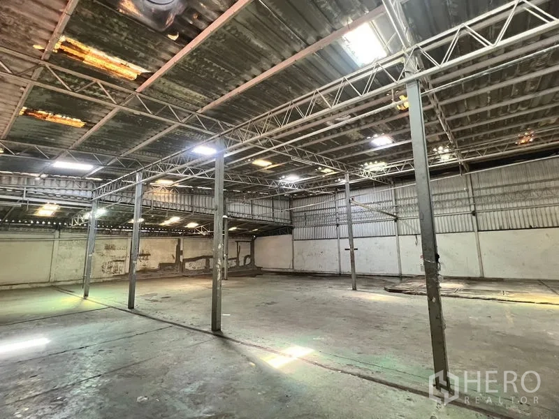 Warehouse for rent in Suan Luang, Bangkok - Open warehouse floor with steel columns and skylights providing natural light.