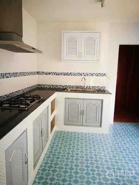 Home Office for rent in Khlong Toei, Bangkok - Kitchen from another angle with gas cooktop, sink and patterned blue floor tiles.
