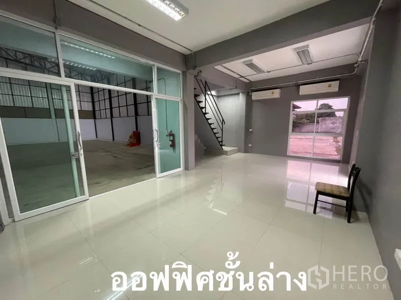 Warehouse for rent in Bang Kapi, Bangkok - Ground-floor office with glossy tiles, glass partition to the warehouse, staircase and air conditioners.