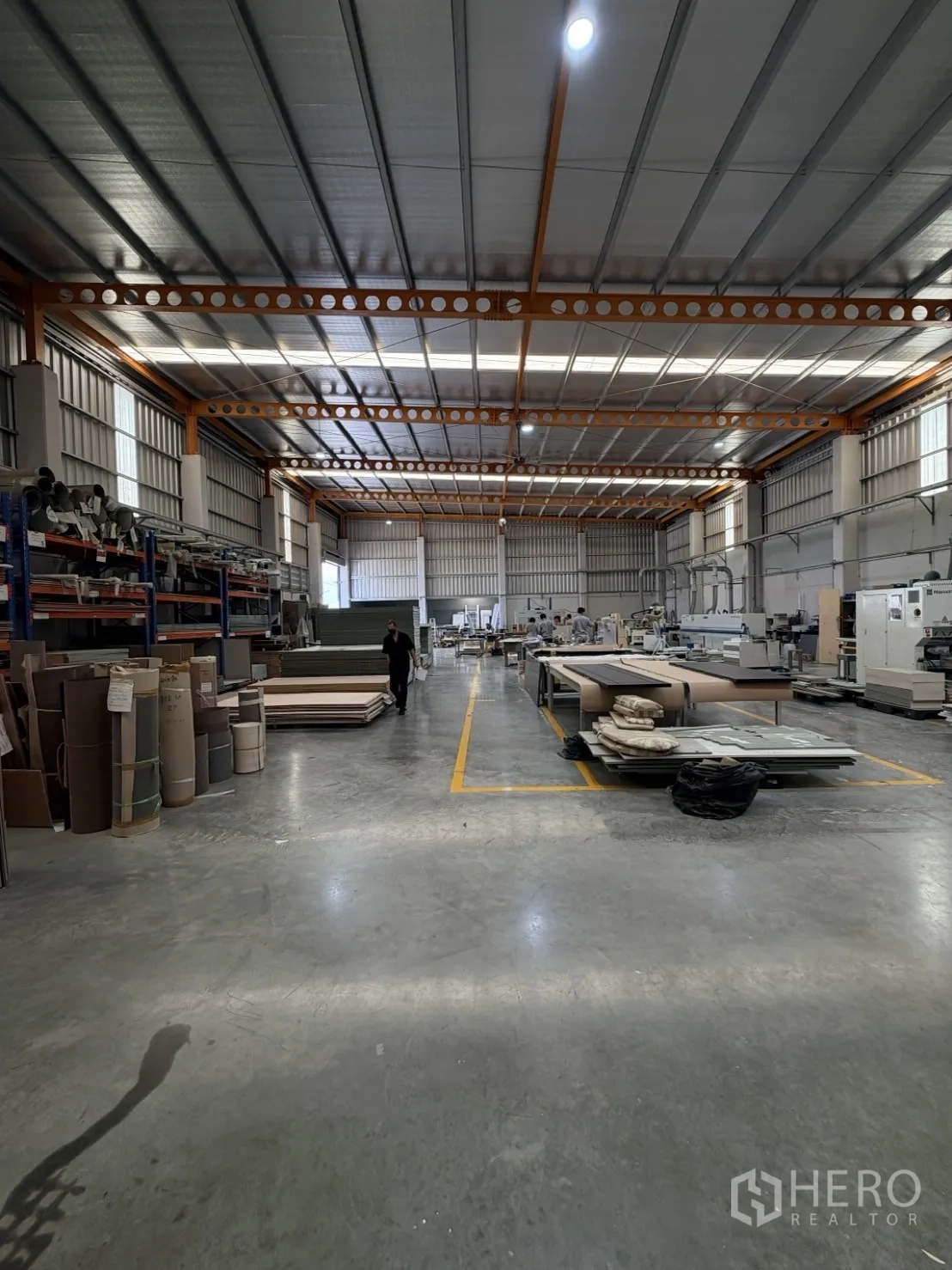Factory for rent or sale in Lam Luk Ka, Pathum Thani - Spacious factory hall with polished concrete floor and orange steel beams.