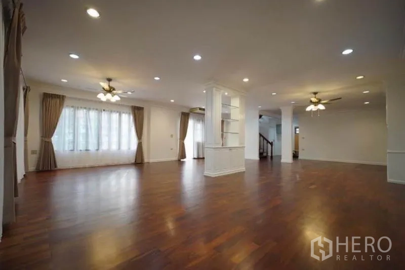Detached House for rent in Bang Phli, Samut Prakan - Expansive living room with columns, shelving and ceiling fans.