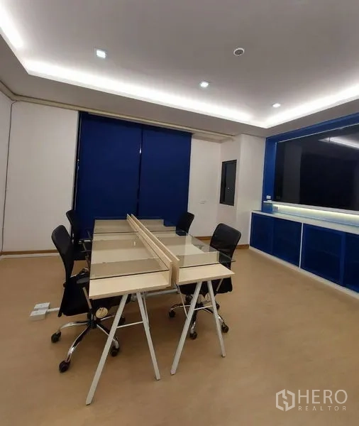 Townhouse for rent in Thanyaburi, Pathum Thani - Modern townhouse facade with tall glass entry and vertical light wood frame at night.