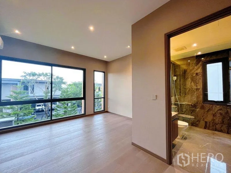 Detached House for sale in Bang Phli, Samut Prakan - Bright bedroom with large windows and an ensuite bathroom finished in stone.