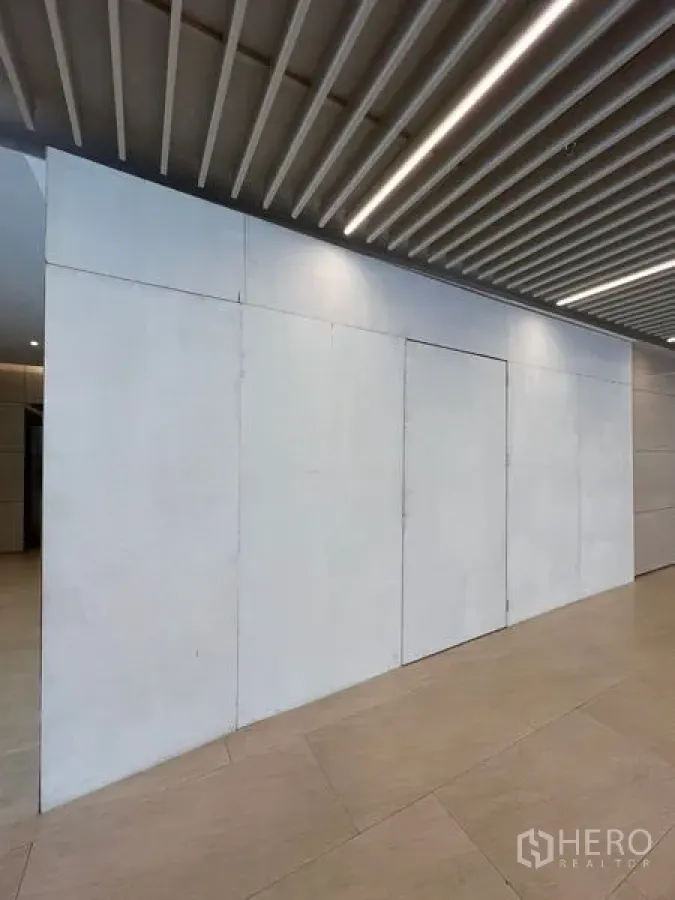 Retail Space for rent in Pathum Wan, Bangkok - Closed retail frontage with white panel door beneath linear ceiling lights in a lobby.