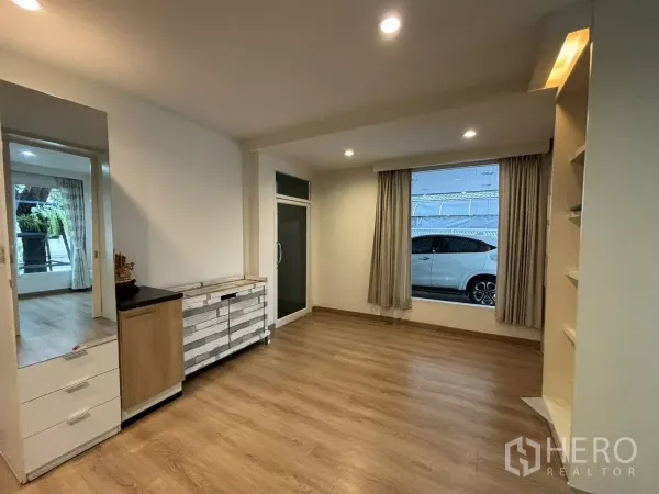 Detached House for rent in Bang Kapi, Bangkok - Spacious room with wood flooring, large window, and built-in cabinets.