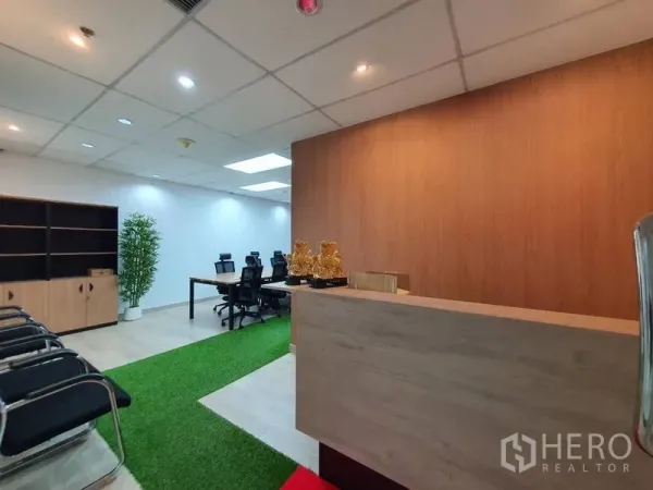 Office Space for rent - Modern Chatuchak office reception with wooden counter, waiting chairs and a green turf walkway leading to a meeting area.