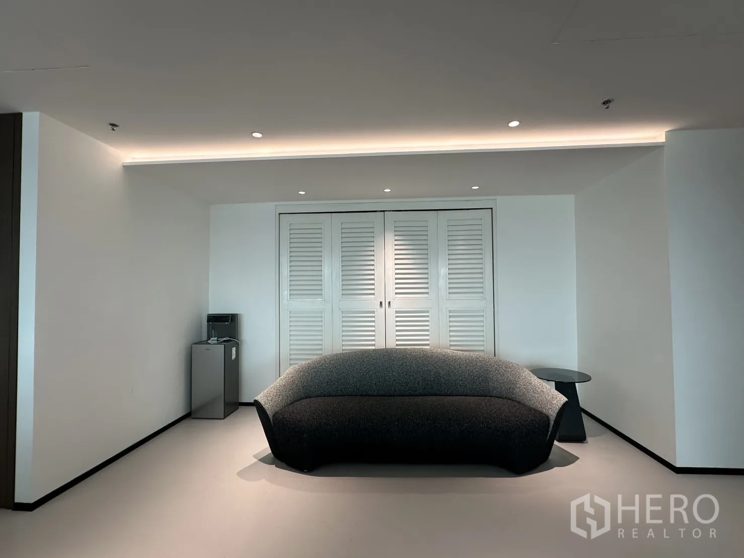 Office Space for rent in Din Daeng, Bangkok - Waiting area with a textured sofa, mini fridge, and shutter-style storage doors.