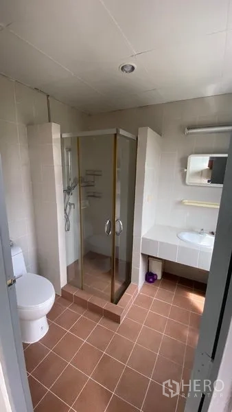 Townhouse for rent in Bang Na, Bangkok - Bathroom with glass shower enclosure, toilet and wide vanity.