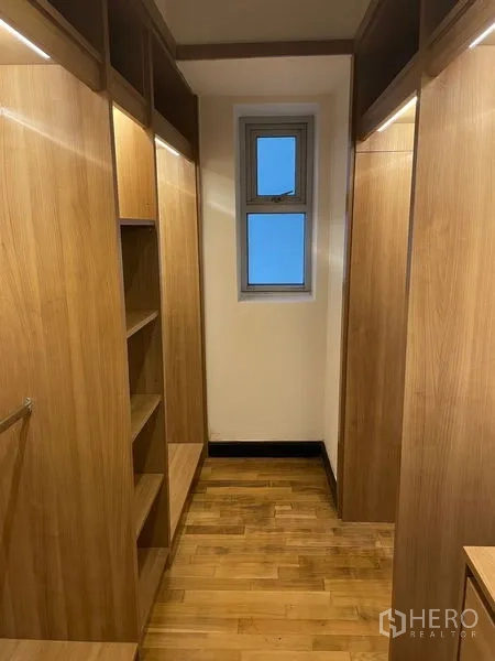 Condominium for rent in Pathum Wan, Bangkok - Walk-in closet with built-in wooden shelving and a small window.