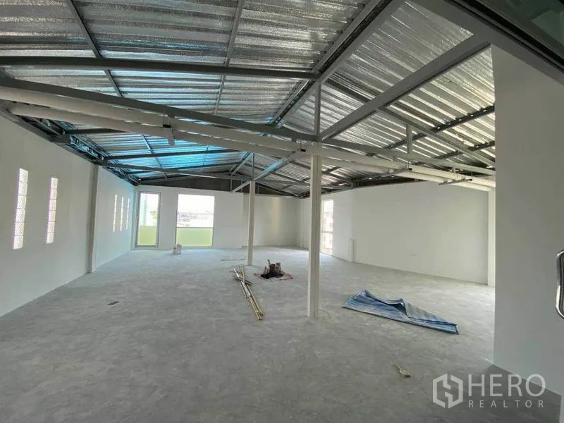 Retail Space for rent in Khlong Toei, Bangkok - Top floor space with exposed metal roof structure and balcony door.