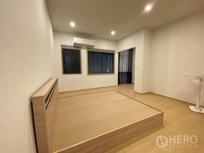 Townhouse for rent in Prawet, Bangkok - Primary bedroom with platform bed frame, air conditioner and balcony alcove.