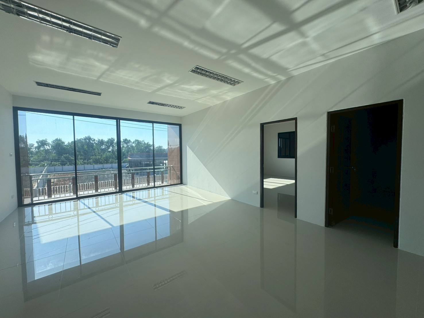 Factory for sale in Mueang Samut Sakhon, Samut Sakhon - Corner office with floor-to-ceiling windows opening to a balcony and two internal rooms.