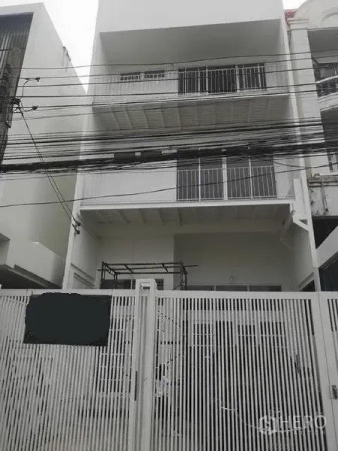 联排别墅 出租或出售在Din Daeng, Bangkok - 多层白色联排外立面，金属围栏与阳台，临街城市电线可见。