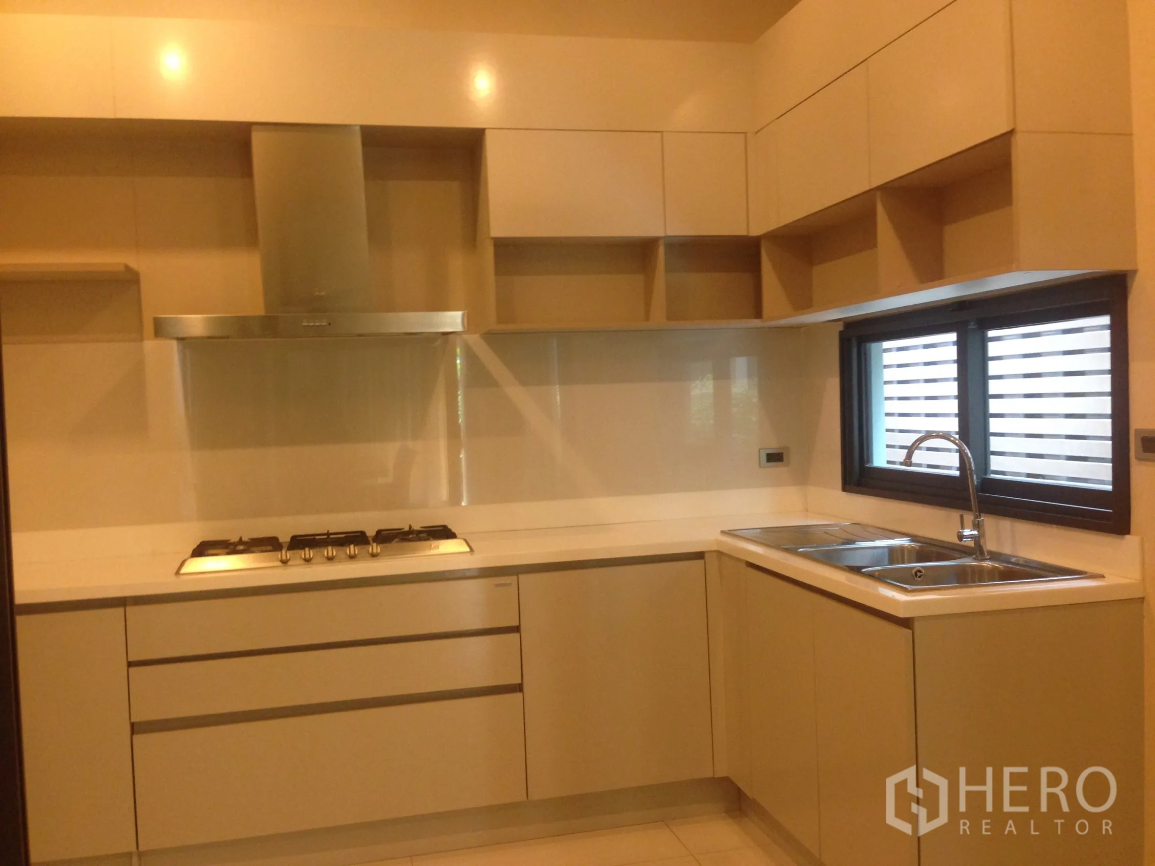 Townhouse for rent in Bang Kapi, Bangkok - L-shaped kitchen view with dual sinks, upper cabinets and window for natural light.