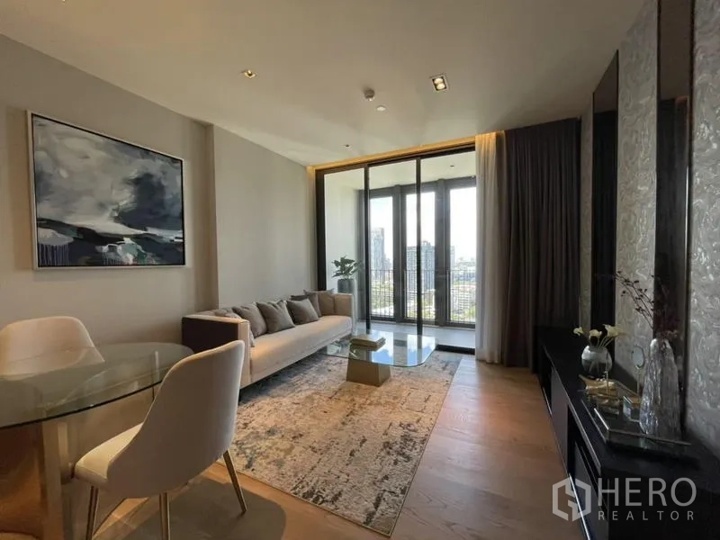 Condominium for rent in Khlong Toei, Bangkok - Living and dining area with wood flooring, glass coffee table, large windows, and skyline outlook.