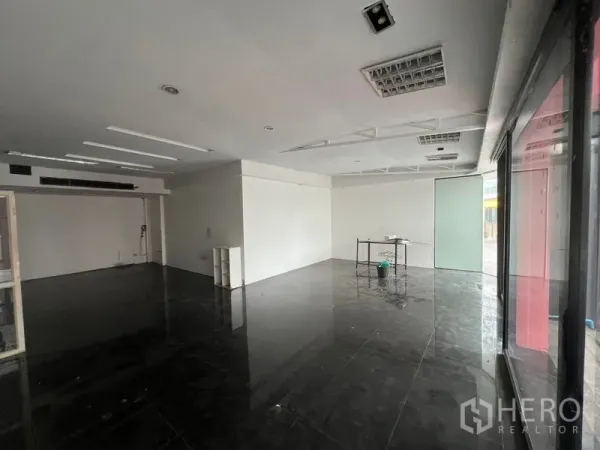 Retail Space for rent in Watthana, Bangkok - Spacious shop floor with large street-facing windows and a small table near a frosted glass door.