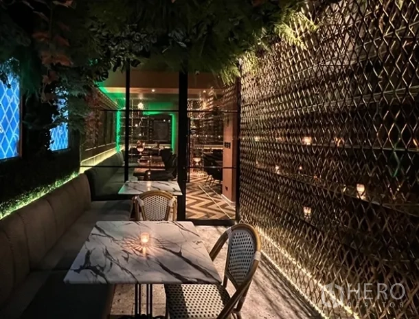 Retail Space for rent in Bang Rak, Bangkok - Narrow dining corridor with marble-top tables, rattan chairs, gold lattice wall and overhead greenery.