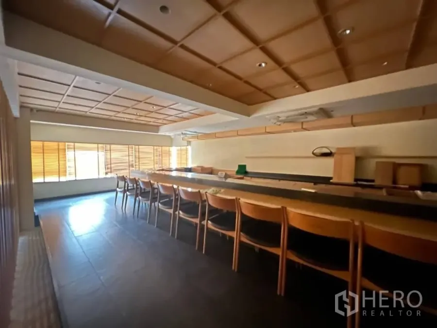 Retail Space for rent - Japanese-style dining room with long wooden sushi bar, coffered ceiling and window blinds in Thonglor retail space.