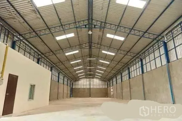 Factory for rent in Mueang Nakhon Pathom, Nakhon Pathom - Spacious factory interior with high steel truss roof, skylights, polished concrete floor and a side office room.