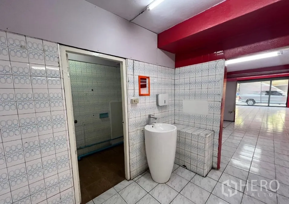 Shophouse for rent in Suan Luang, Bangkok - Ground-floor wash area with pedestal sink, tiled walls and view to the shopfront.