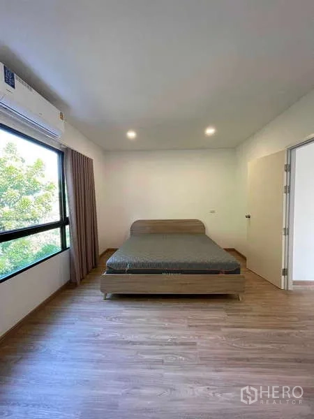 Townhouse for rent or sale in Bang Kapi, Bangkok - Front view of master bedroom with double bed, bright window and air conditioning.