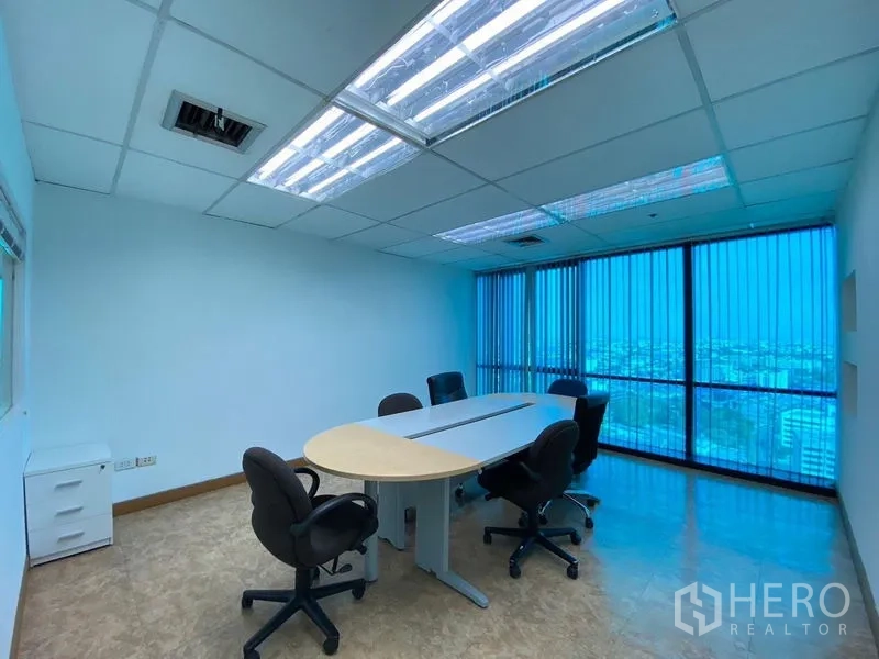 Office Space for rent - Glass-walled meeting room with oval table and skyline views through vertical blinds.