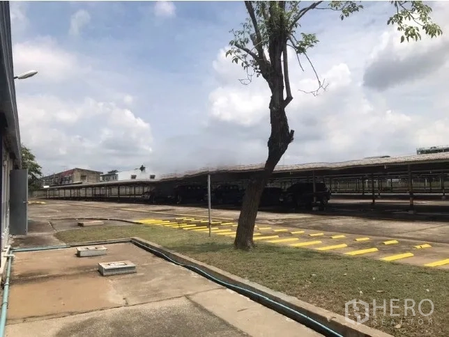 Factory for rent in Bang Bua Thong, Nonthaburi - Expansive paved yard with long covered shelters and traffic markings.