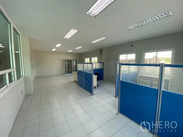Factory for rent or sale in Samut Sakhon - Bright tiled office with fluorescent lighting and blue partitioned workstations overlooking the site.